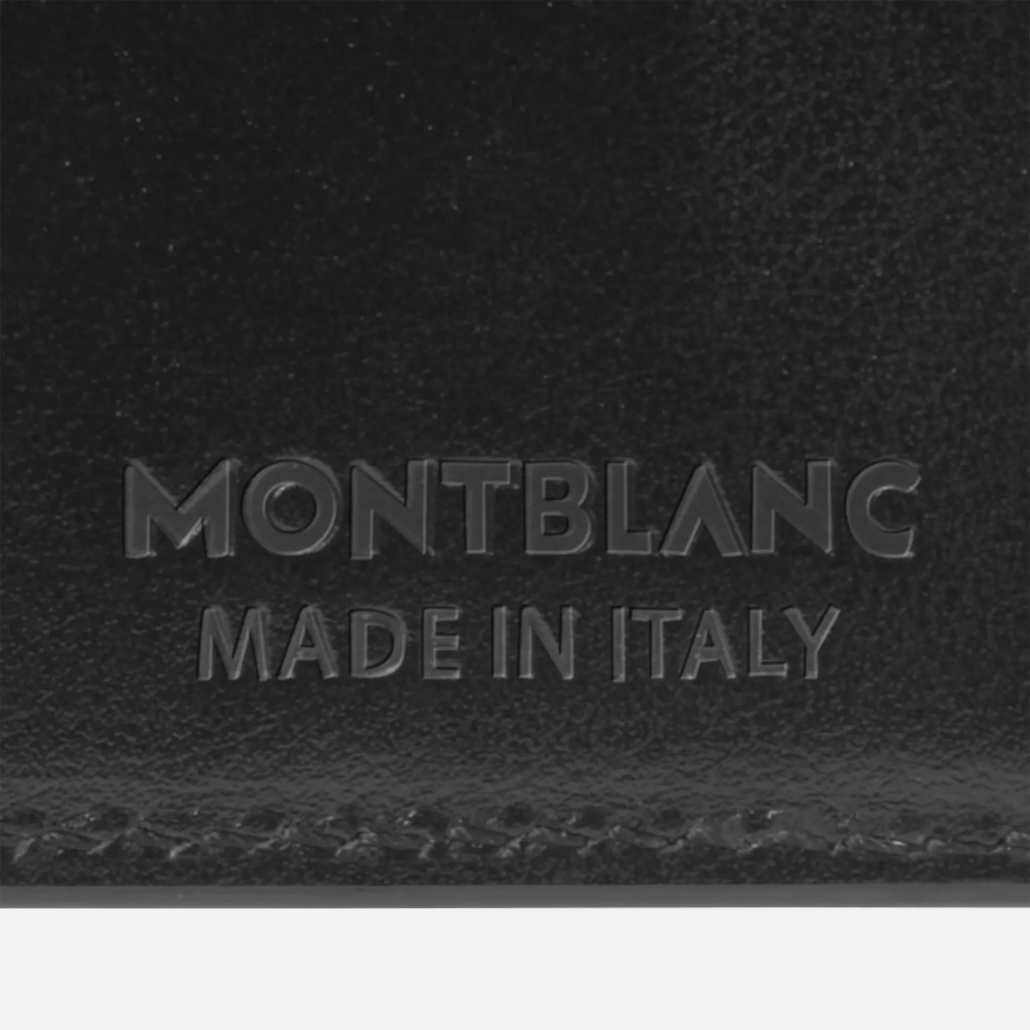 Dettaglio del marchio a secco Montblanc con dicitura Made in Italy sul portafoglio in pelle.