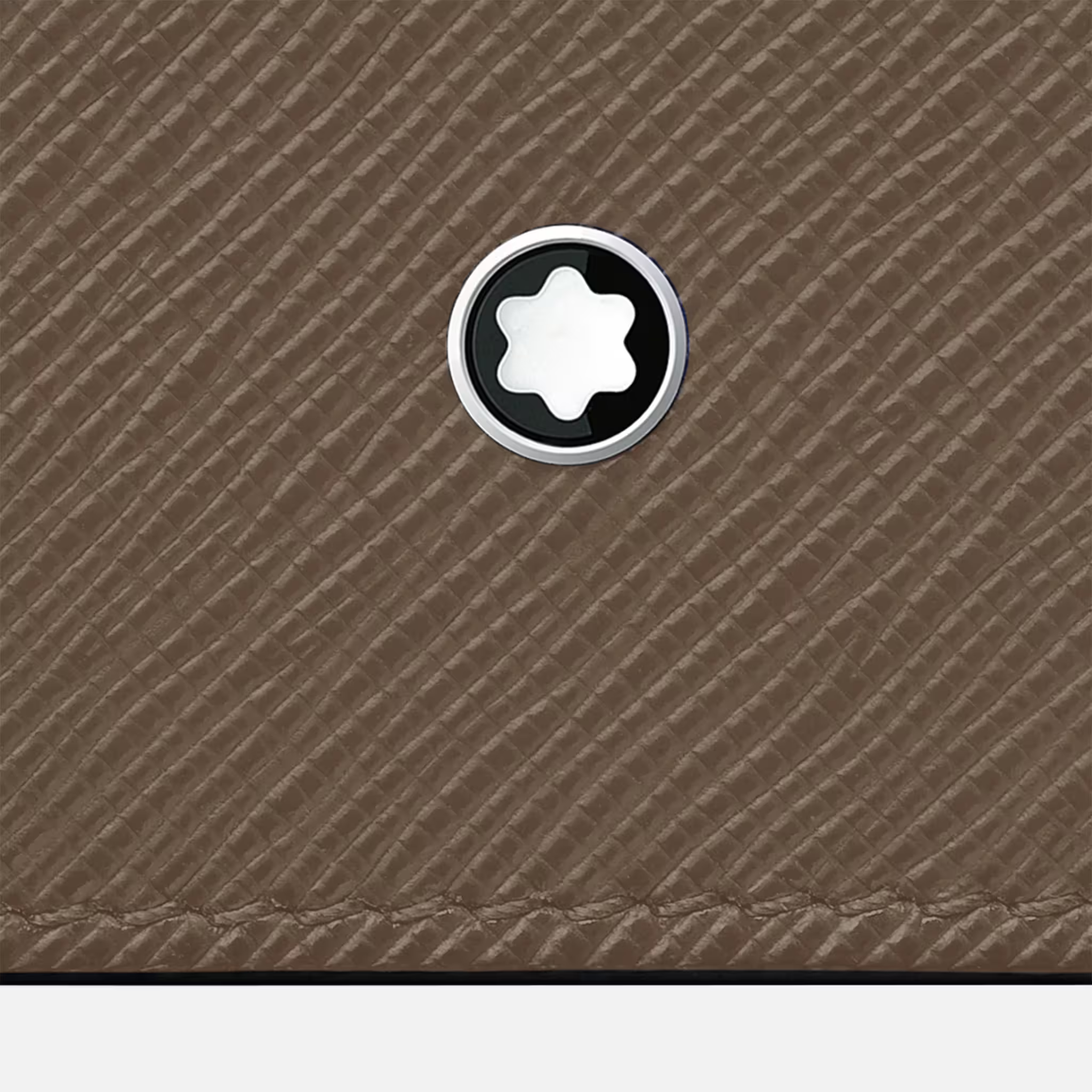 Dettaglio dell’emblema Montblanc su pelle saffiano color Mastic, con texture visibile in primo piano