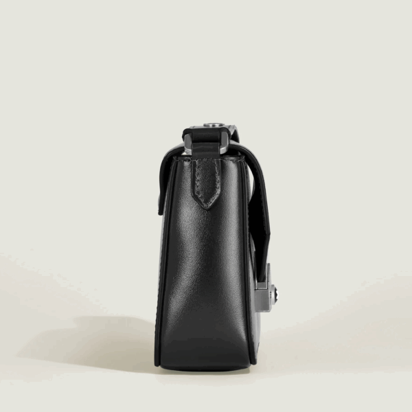 Handbag strutturata in pelle nera con manico superiore e cuciture visibili su sfondo chiaro