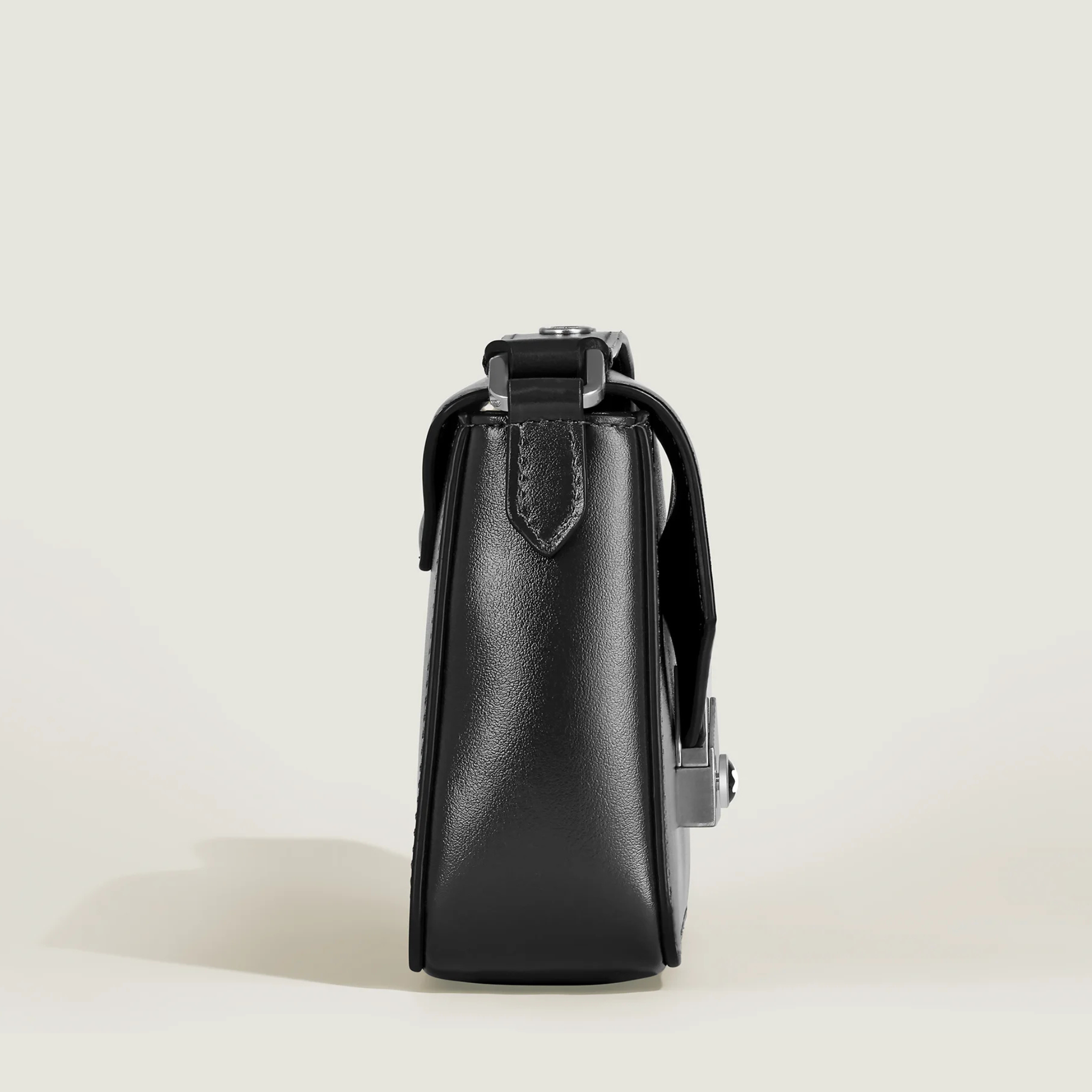 Handbag strutturata in pelle nera con manico superiore e cuciture visibili su sfondo chiaro