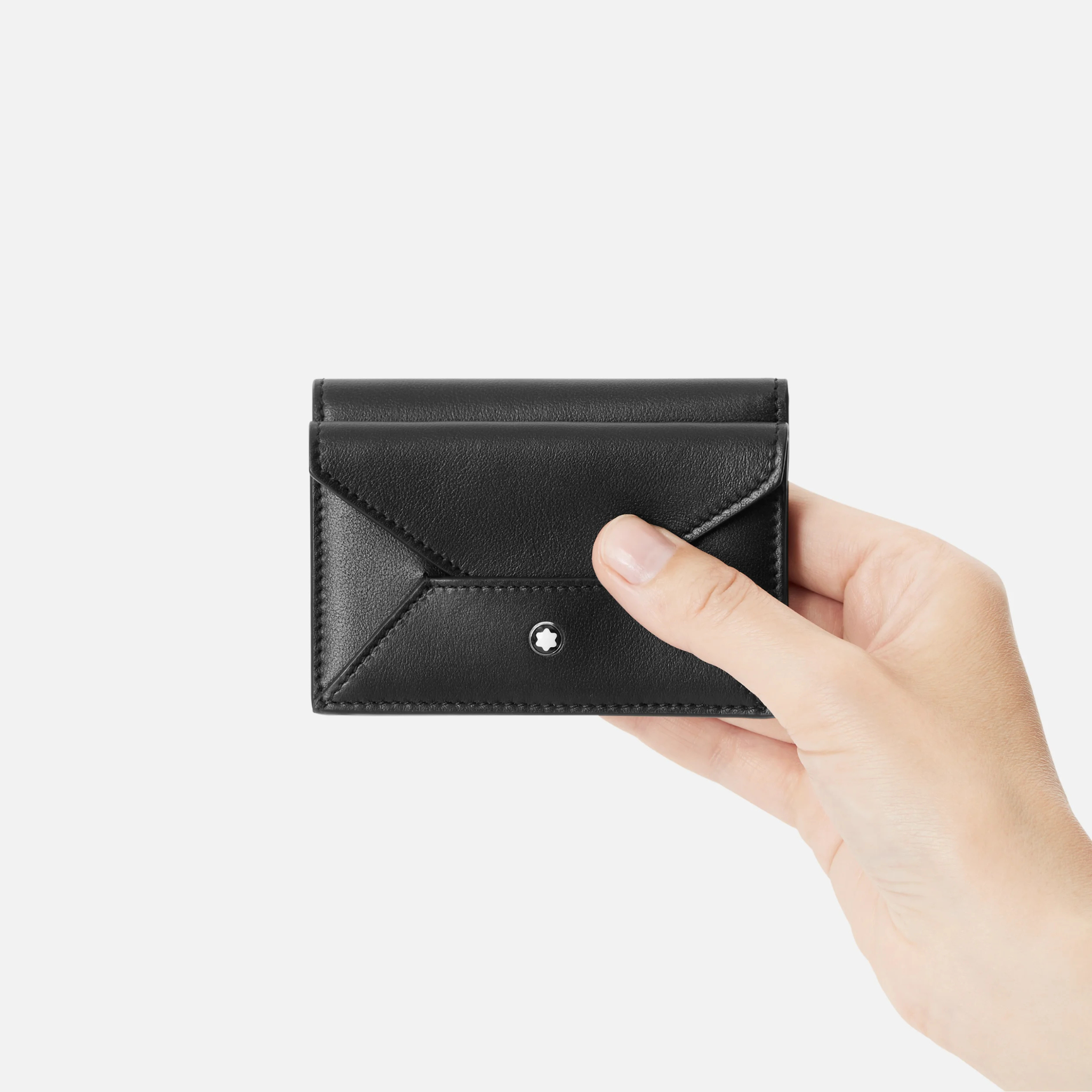 Porta carte Montblanc Soft – Pelle nera compatta con chiusura a patta Porta carte Montblanc Soft nero tenuto in mano con chiusura a patta ed emblema