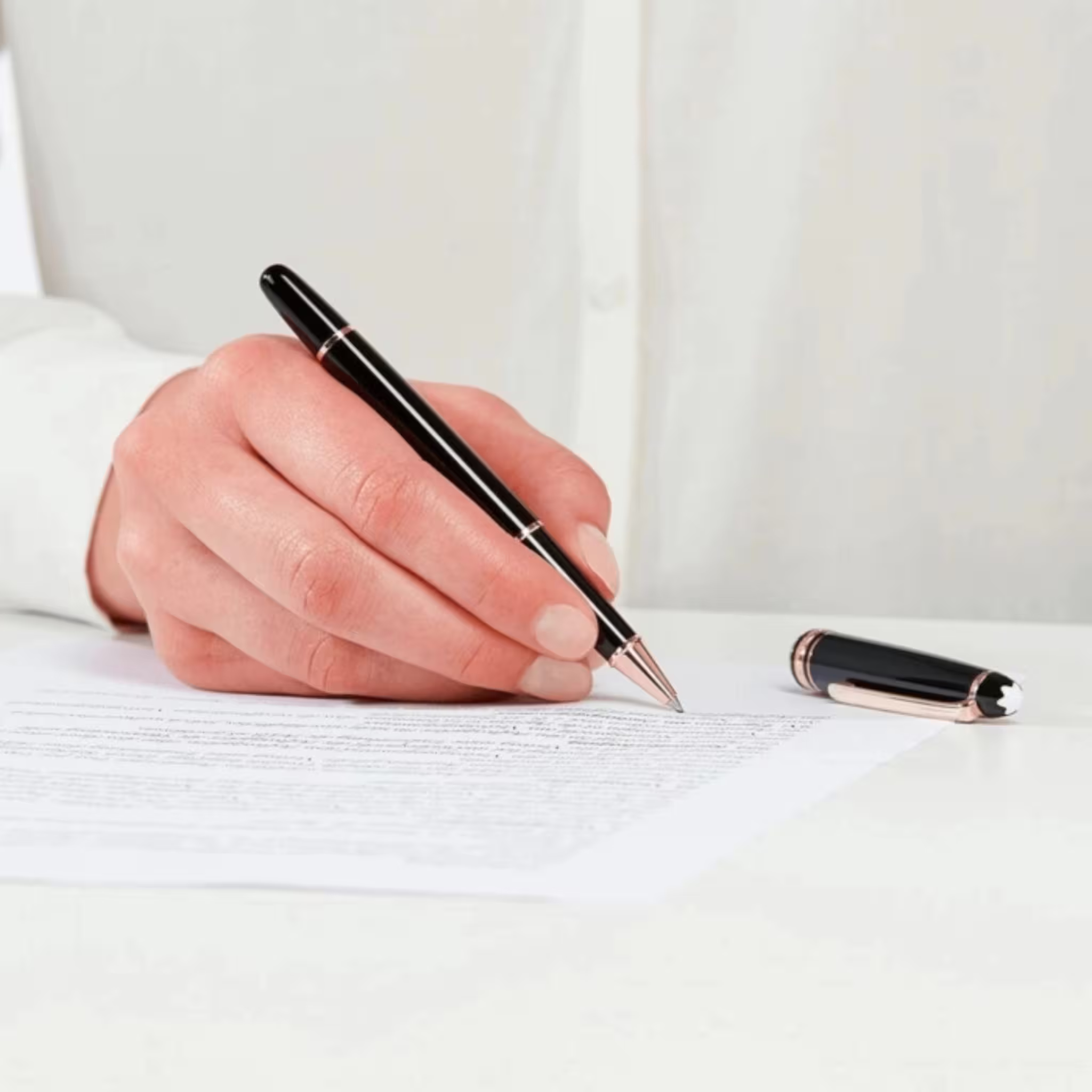 Mano che firma un documento con penna Montblanc Roller Meisterstück nera e oro rosa